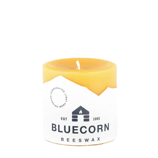 Bluecorn Beeswax pillar candle with a label on it on a white background.