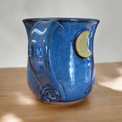 Blue ceramic mug with a moon design on a wooden surface