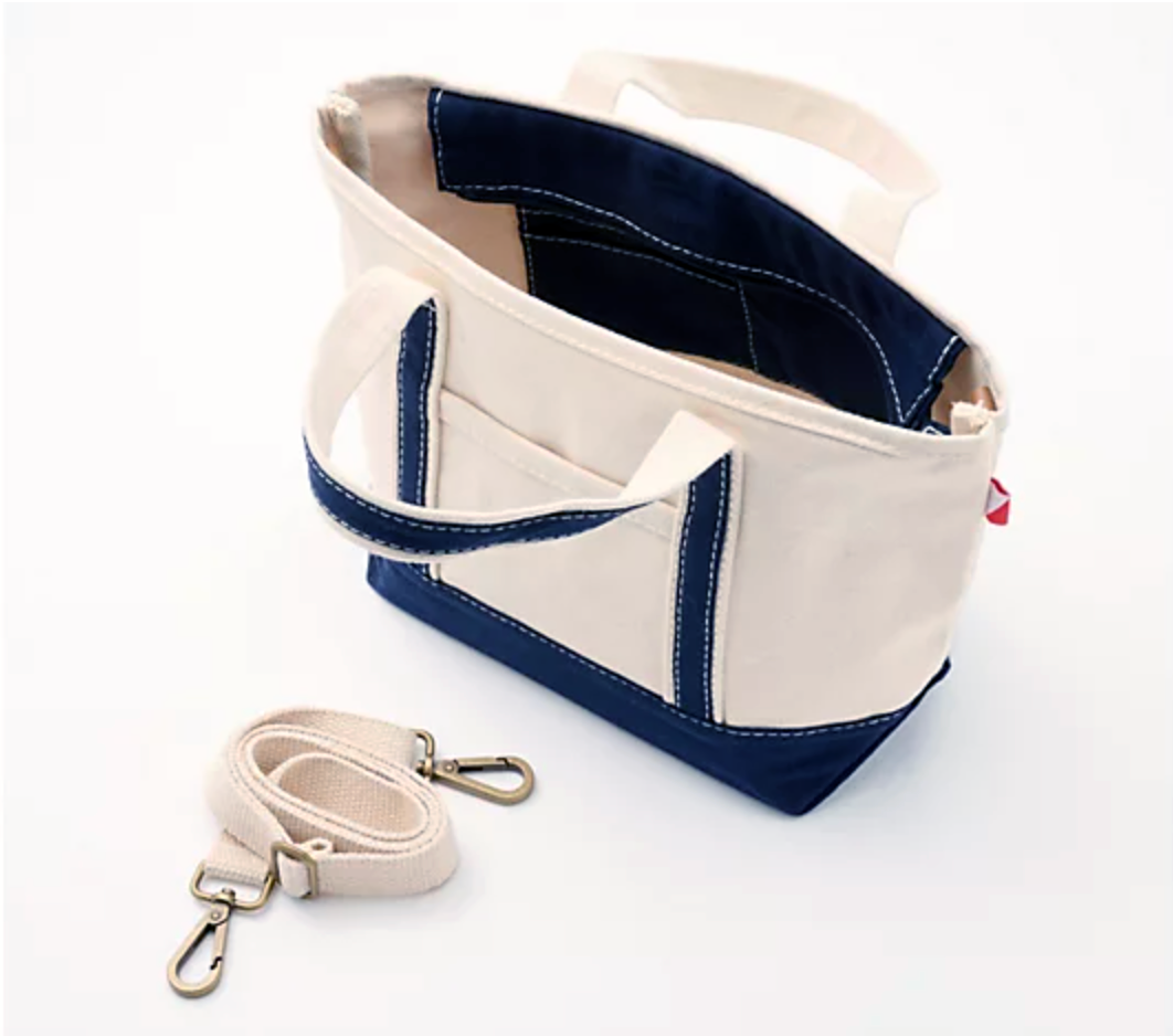Beige tote bag with navy accents and matching strap on a white background