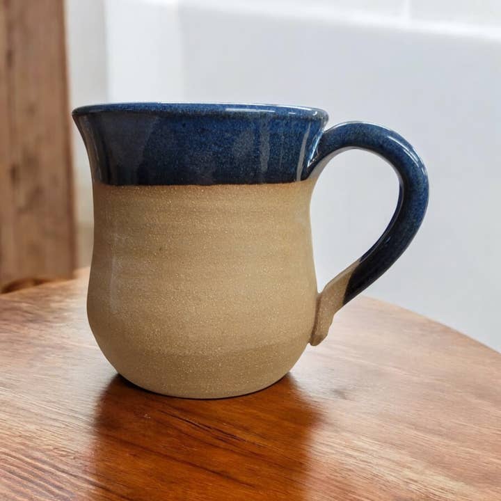 Ceramic mug with blue interior and beige exterior on a wooden surface