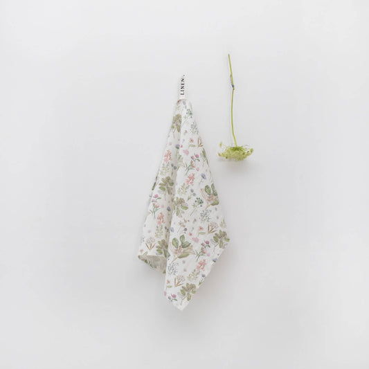 Floral-patterned towel hanging on a white wall with a Queen Anne's Lace stem