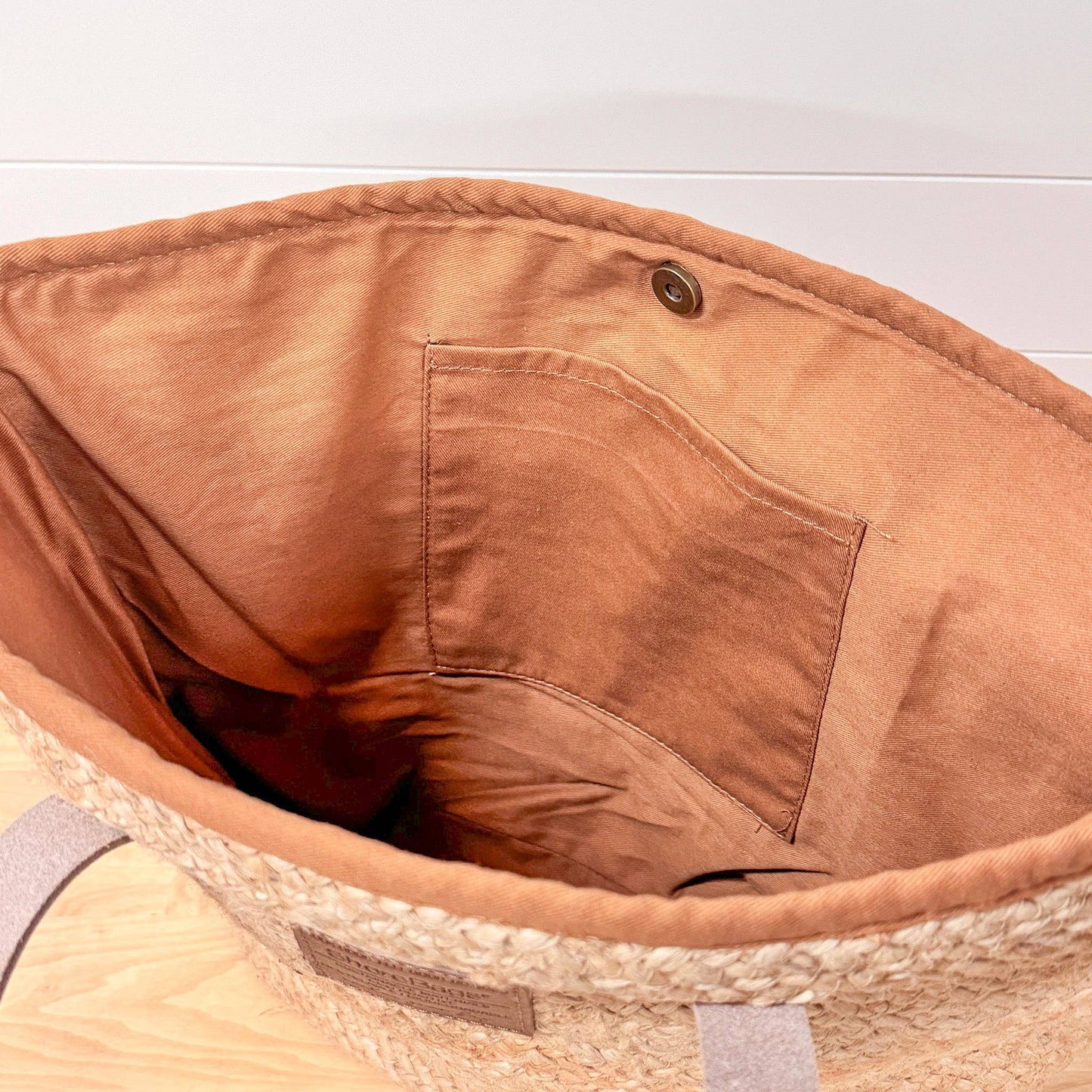 Close-up of a brown bag with a pocket on a light wooden surface.