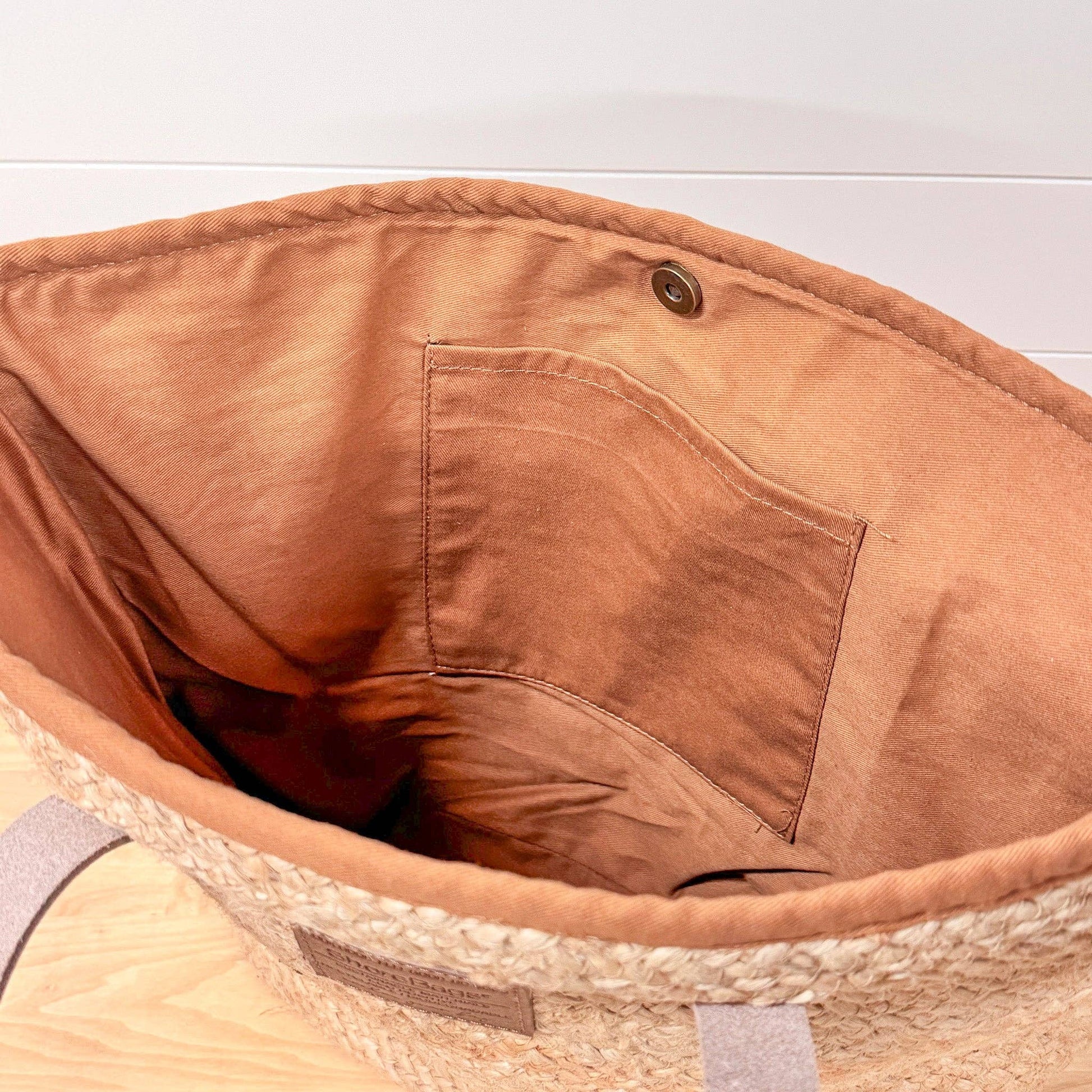 Close-up of a brown bag with a pocket on a light wooden surface.