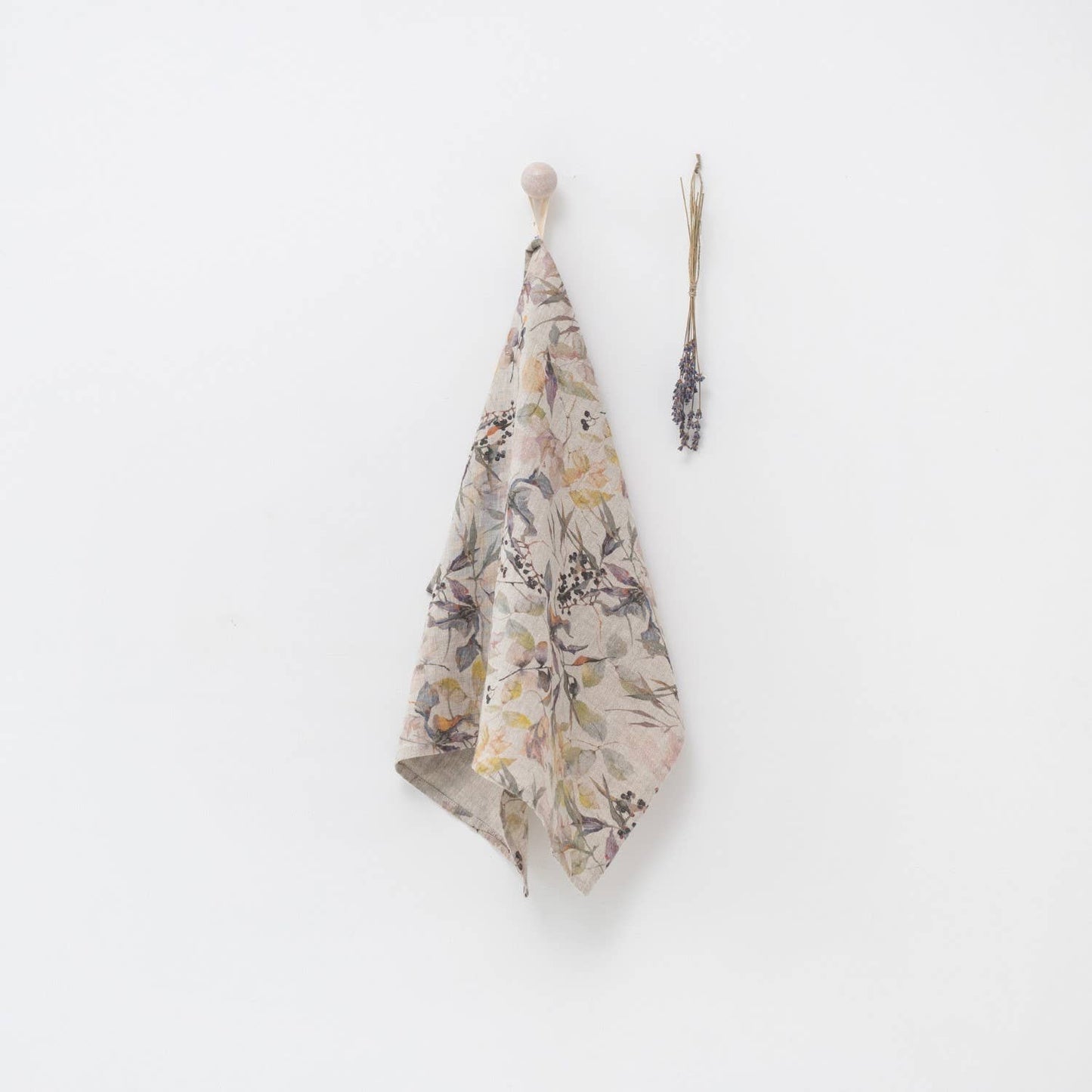 Floral-patterned towel hanging on a hook against a white wall