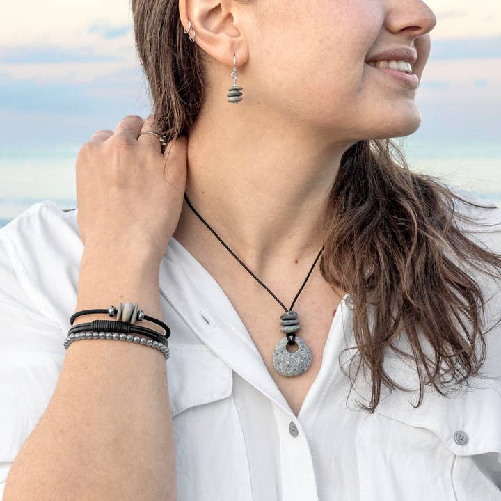 Woman wearing a necklace, bracelets and earrings with a blurred natural background