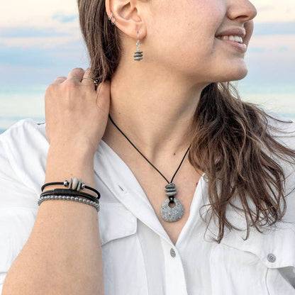 Woman wearing a necklace, bracelets and earrings with a blurred natural background
