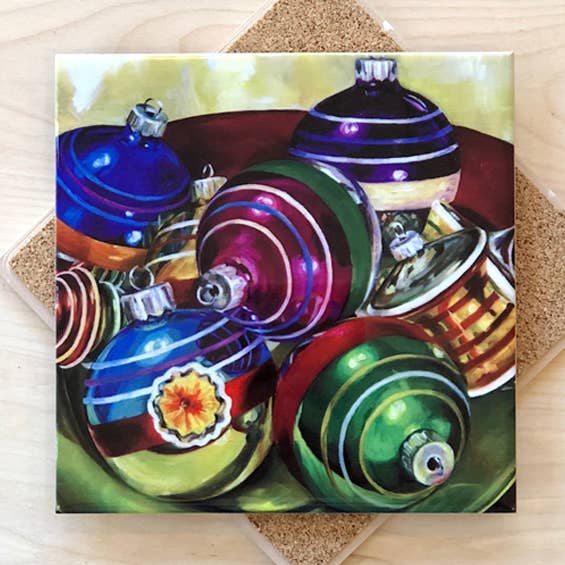 Trivet with a painting of colorful Christmas ornaments on a textured surface.
