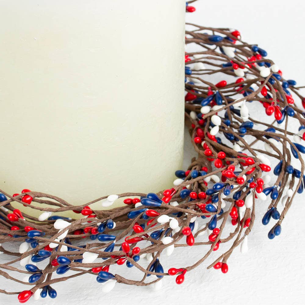 Decorative wreath with red, blue, and white berries on a plain background