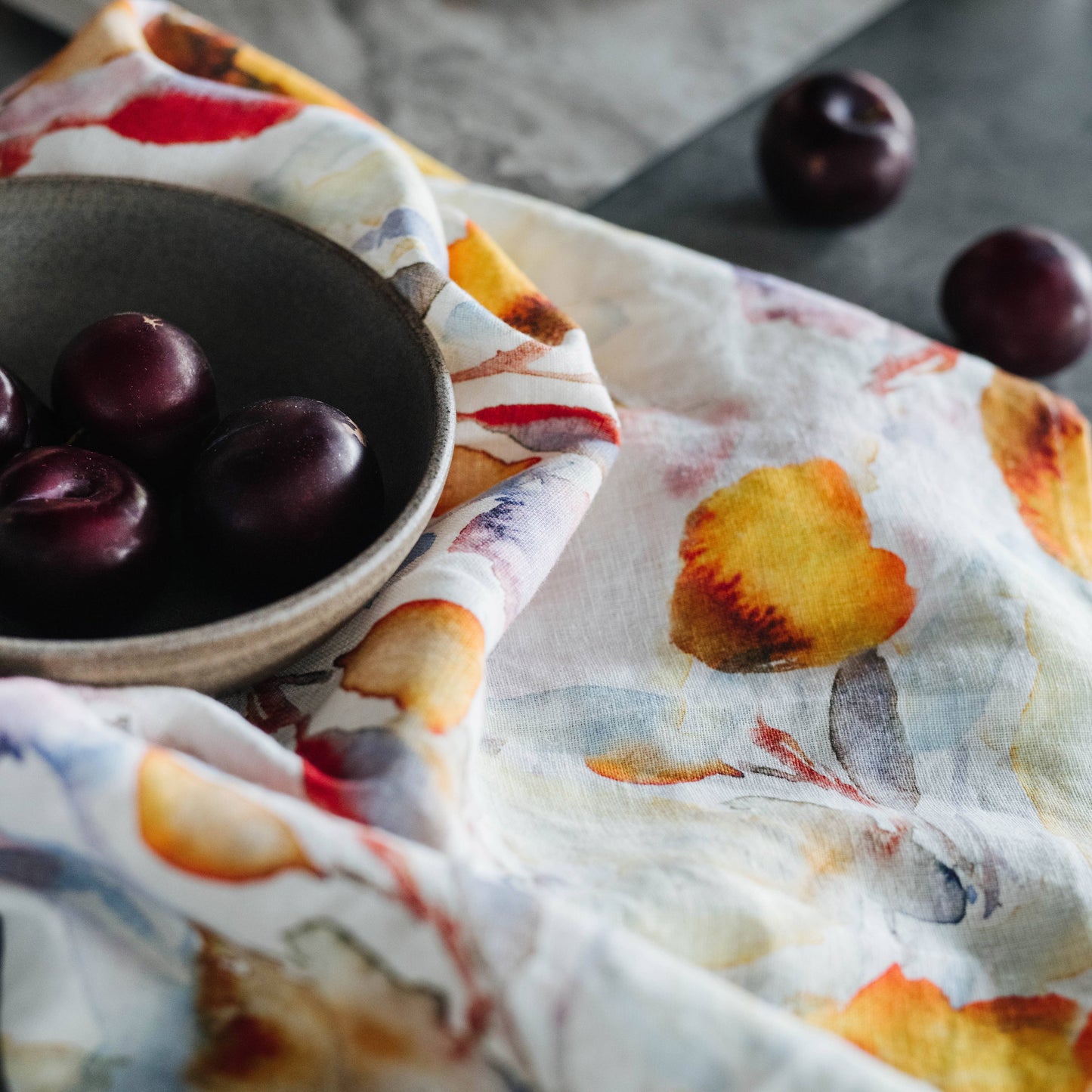 Plum fruits on a decorative tea towel with a floral pattern