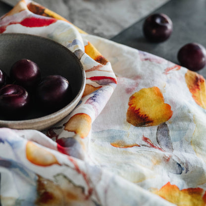 Plum fruits on a decorative tea towel with a floral pattern