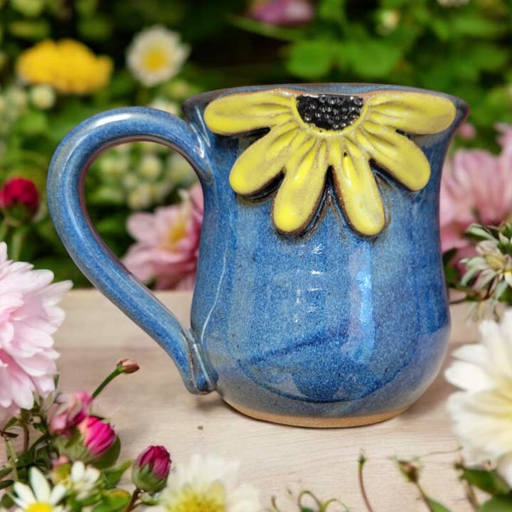 Blue ceramic mug with a yellow black eyed Susan design on a floral background
