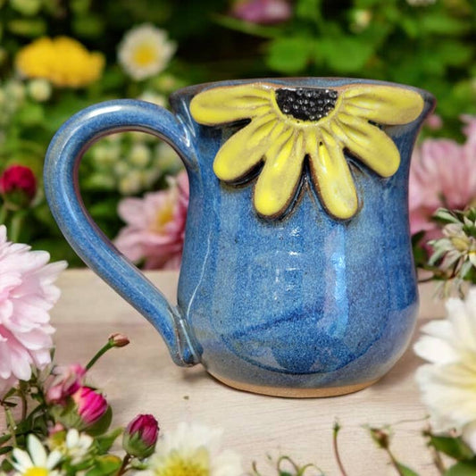 Blue ceramic mug with a yellow black eyed Susan design on a floral background