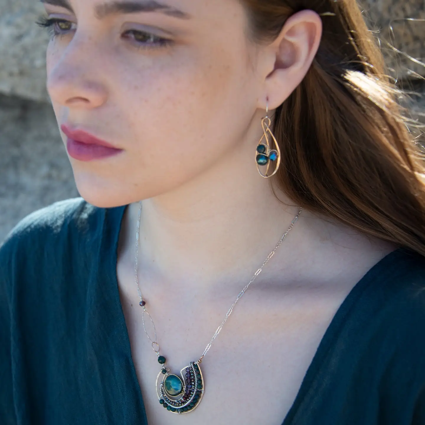 Woman wearing a necklace and earrings with a blurred background