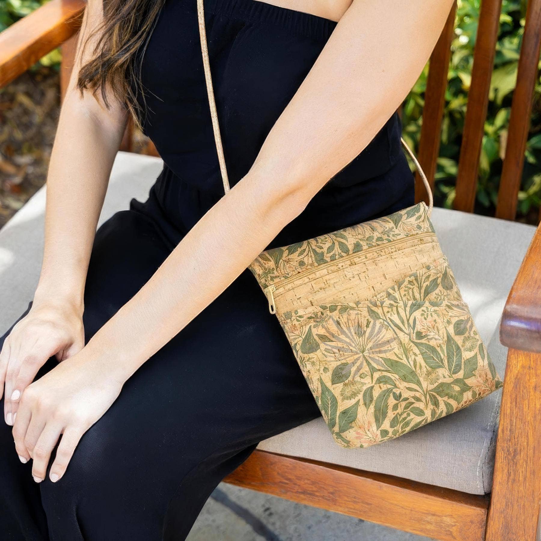 Person sitting outdoors with a cork handbag featuring green leaf pattern