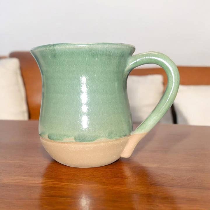 Green ceramic mug on a wooden table with a neutral background
