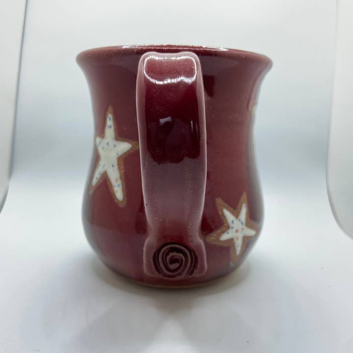 Red ceramic mug with star designs on a white background
