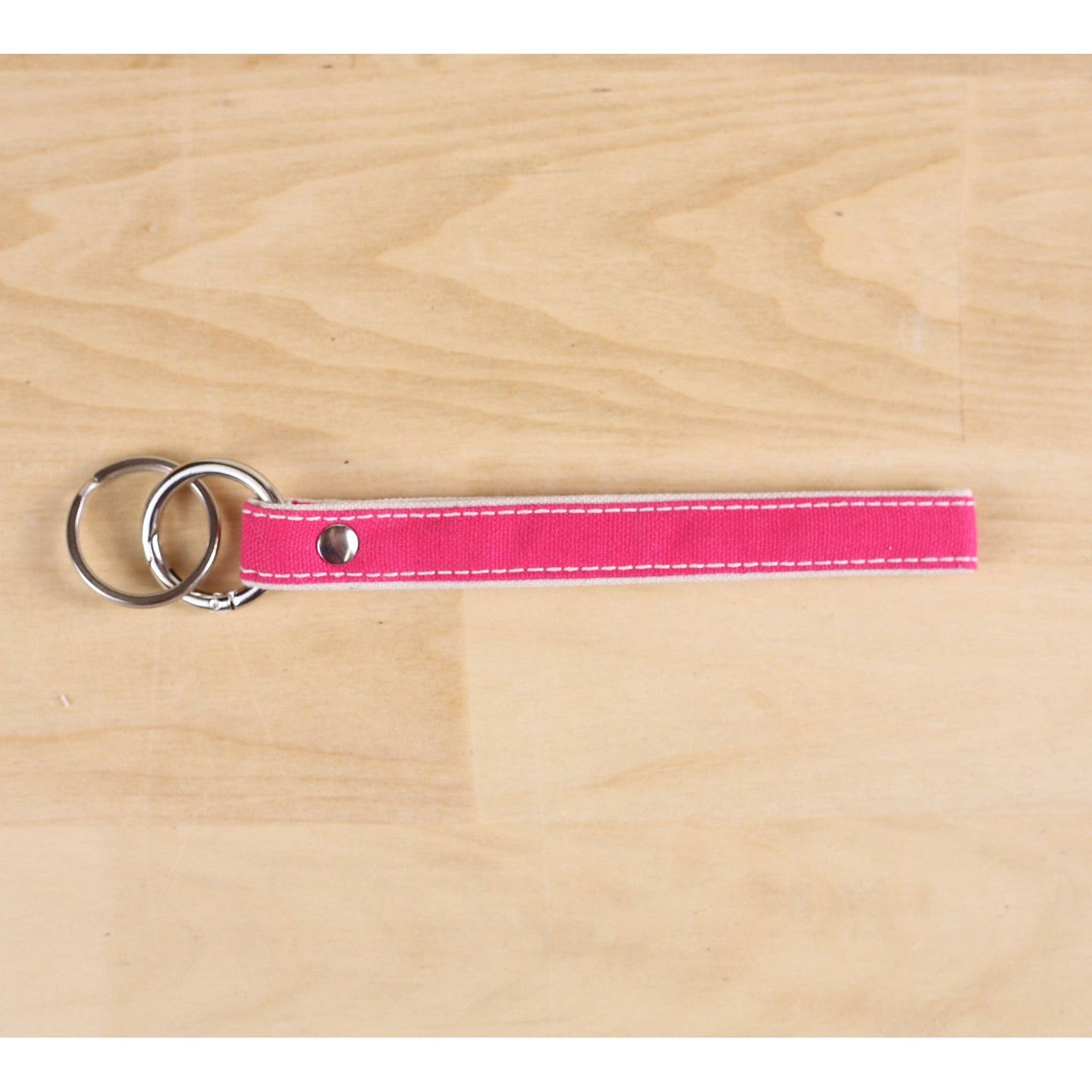 Pink keychain with metal rings on a wooden surface