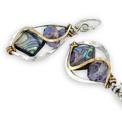 Pair of earrings with purple gemstones and gold accents on a white background