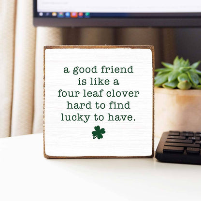 Decorative sign with a four-leaf clover and text on a desk.