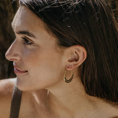 Close-up of a woman wearing a gold hoop earring with a blurred background