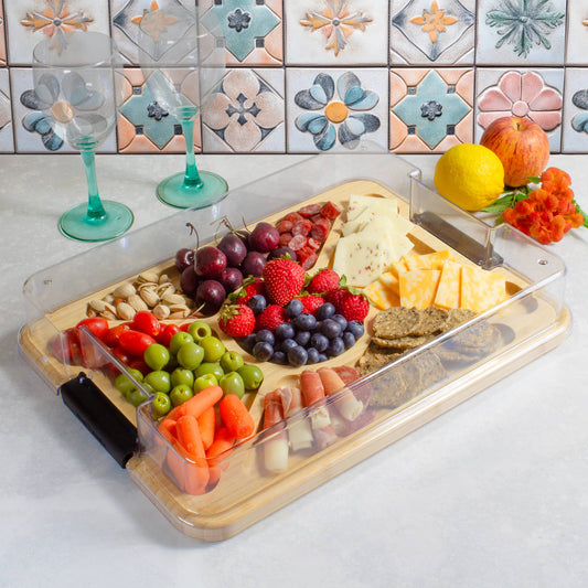 Plated charcuterie board with fruits, cheese, and vegetables on a decorative tile background
