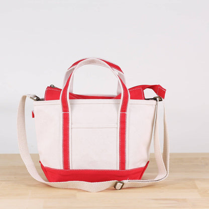 White tote bag with red accents on a wooden surface and light gray background