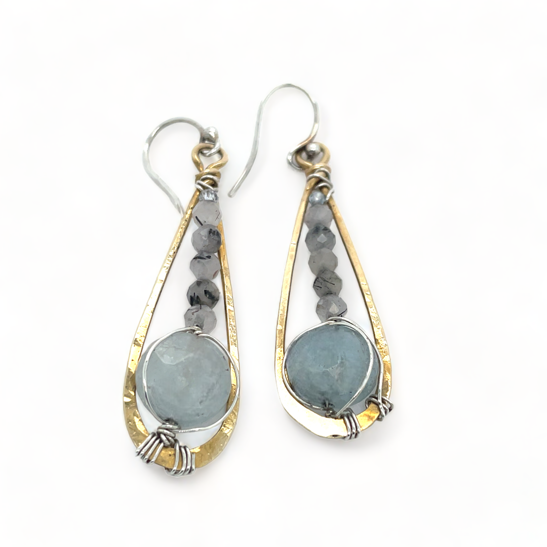 Pair of earrings with teardrop-shaped stones and gold and silver frames on a white background