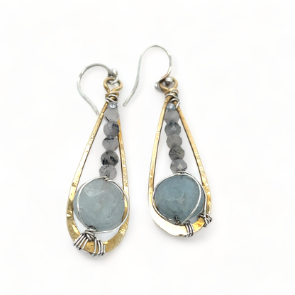 Pair of earrings with teardrop-shaped stones and gold and silver frames on a white background