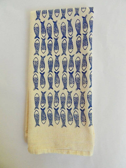 A folded beige cotton tea towel with a dark blue fish print
