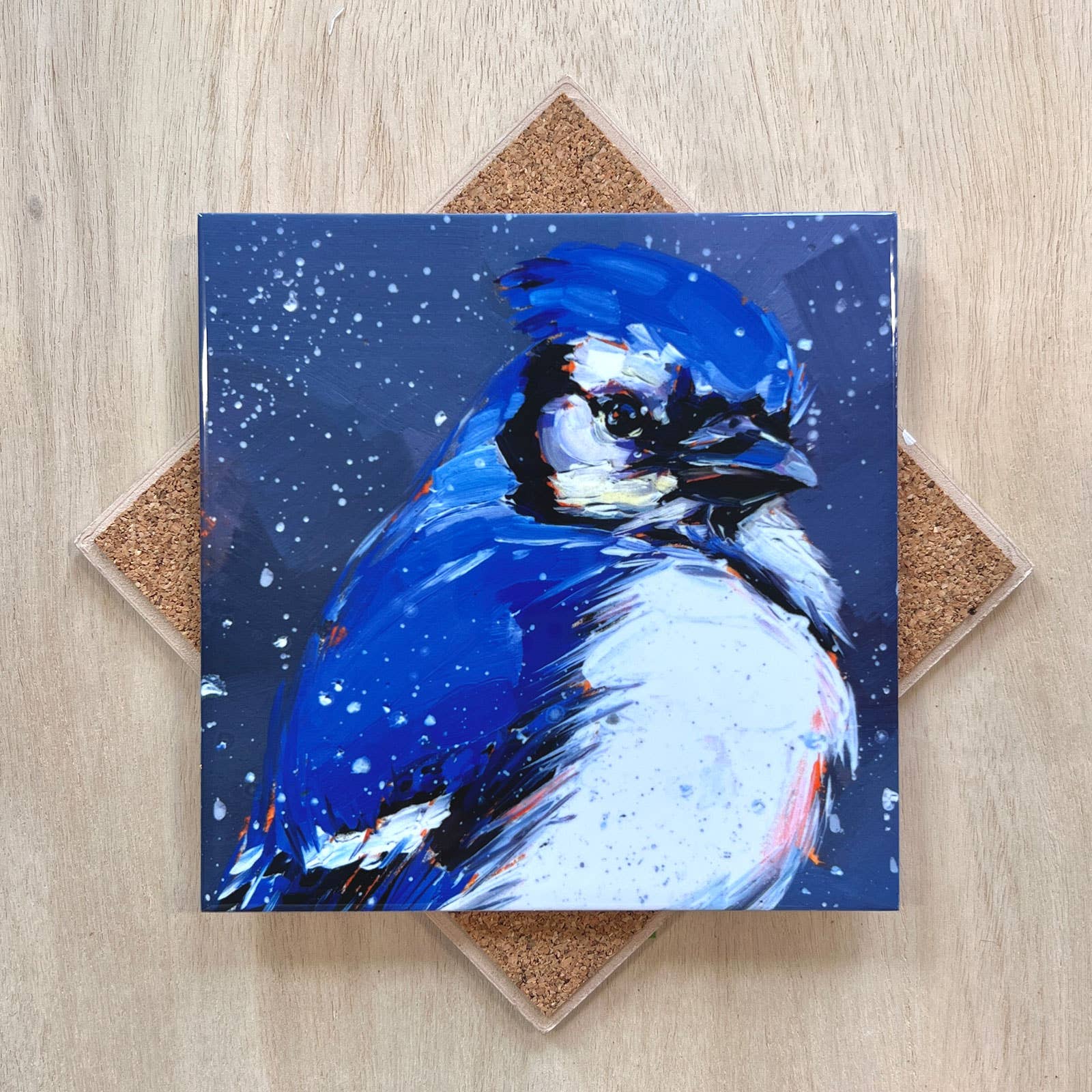 Trivet with a blue jay illustration on a wooden surface.