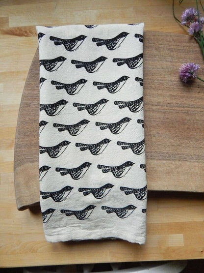Folded towel with black bird pattern on a wooden surface