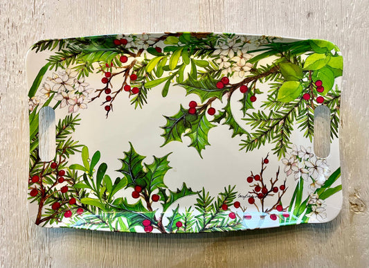 Decorative glass cutting board with holly and berry design on a wooden surface