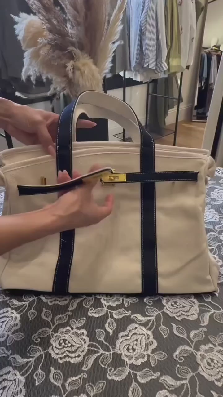 Hands demonstrating the interior flap closure on a navy canvas boat tote, showing how the bag closes securely at the top