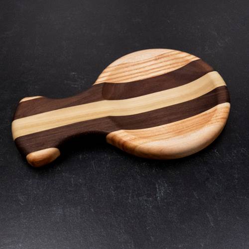 Wooden spoon rest with striped pattern on a dark surface