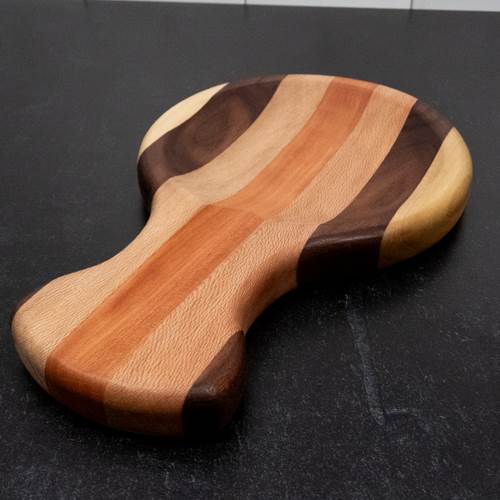 Wooden spoon rest with striped pattern on a dark surface