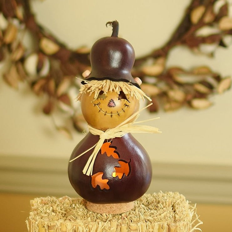 Decorative scarecrow gourd with a face on a hay bale with a blurred background
