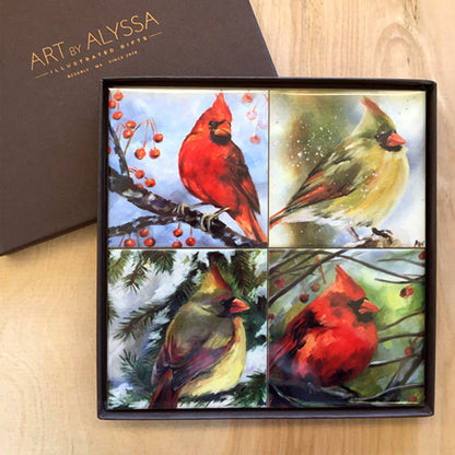A set of four ceramic tile coasters with cork backing, each featuring a different image of cardinals from original oil paintings, packaged in a gift box with 'Art by Alyssa' logo.