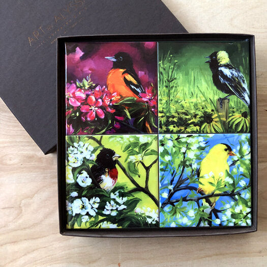 A set of four ceramic tile coasters with cork backing, each featuring a colorful bird and floral design, displayed in a gift box with a gold stamp logo.