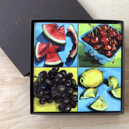A set of four ceramic tile coasters with cork backing, each featuring a colorful fruit motif, displayed in a high-quality gift box.