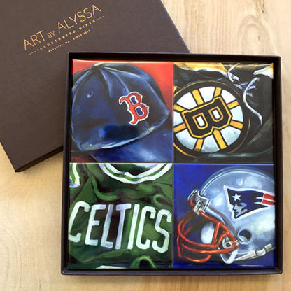 A set of four ceramic tile coasters with cork backing, each featuring a different sports team logo, displayed in a gift box with 'Art by Alyssa' branding.