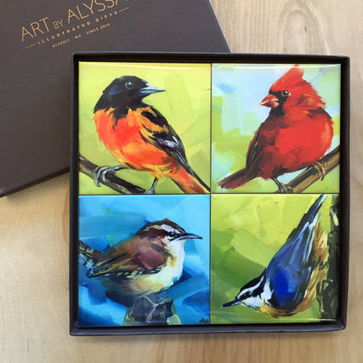 A set of four ceramic tile coasters with cork backing, each featuring a colorful illustration of a bird, displayed in a presentation box with 'Art by Alyssa' branding.