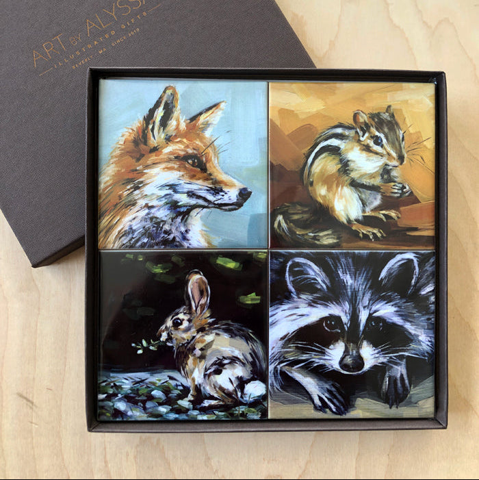 A set of four ceramic tile coasters with cork backing, each featuring a different animal painting, displayed in a gift box.
