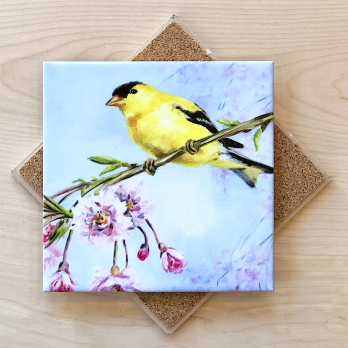 A 6-inch square trivet with an image of a goldfinch perched on a branch with pink flowers, and a cork backing.