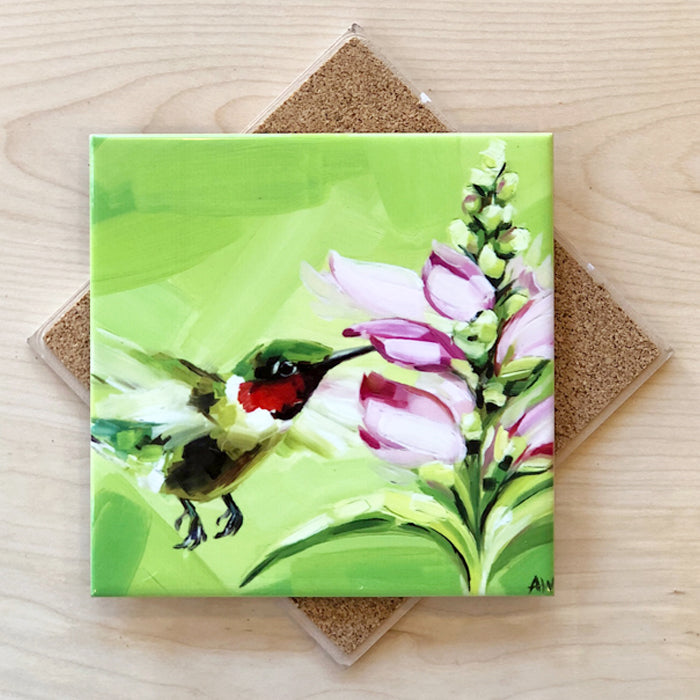 A 6-inch square trivet with an image of a hummingbird feeding on pink foxglove flowers, with a cork backing.