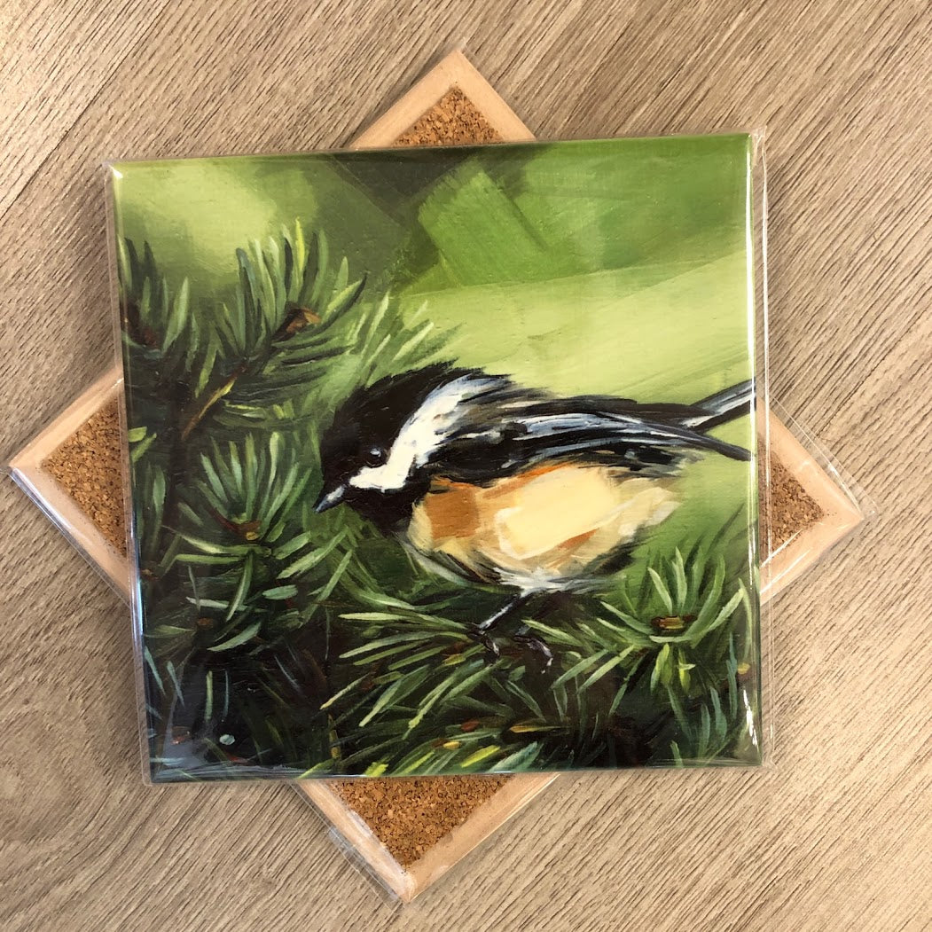 A 6-inch square tile trivet with an image of a chickadee bird perched on pine needles, featuring a cork backing.